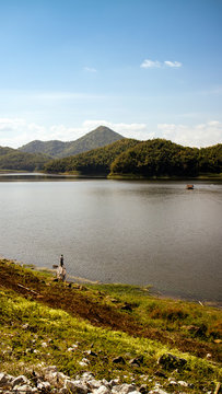 scanic view of lake with man fishing against mountain and clear sky
