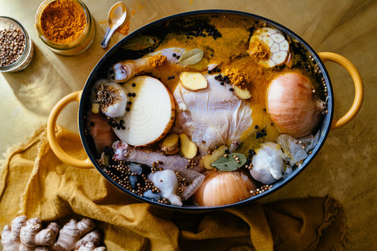 Chicken soup prep with spices in yellow dutch oven