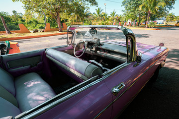 A classic pink retro car is parked on road in the resort town of Varadero. Cuba.