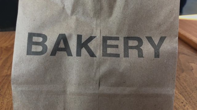 Camera tracking right to left zoomed on paper bag with the word bakery printed on it