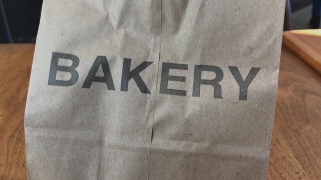 Camera tracking right to left on paper bag with the word bakery printed on it