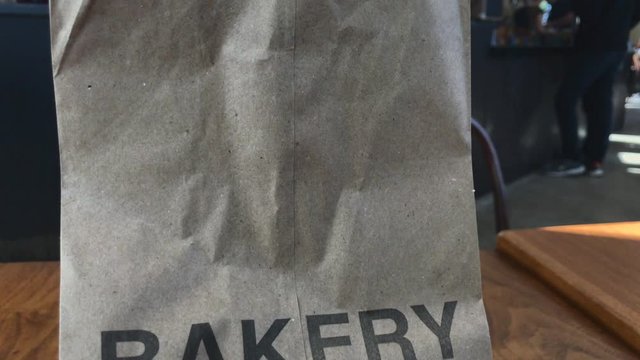 Camera tracking down on paper bag with the word bakery printed on it
