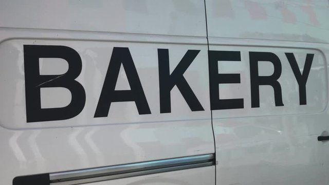 Camera panning down from sky to white van with bakery written on it