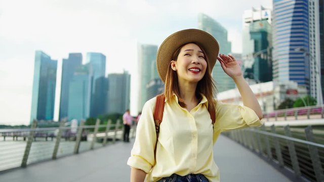 4k Footage. Asian woman traveler with backpack and hat traveling into Singapore city downtown. Travelling in Singapore concept.