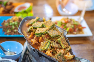Group of female friends enjoy eating with acacia pennata omelette sour soup in fish shape hot pot in the restaurant. Selective focus.