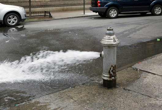 Fire hydrant open without water saving cap in Bronx NY community during summer