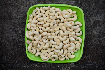 Green plate with cashew nuts on dark background