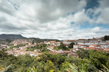 Fototapeta na wymiar Panorama of colonial mining city centre Ouro Preto in Minas Gerais, Brazil, with surrounding mountains in the background seen from a high vantage point against a blue sky with dramatic clouds above