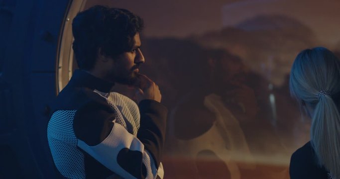 Astronauts talking by Martian base window