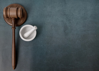 Concept for legal system and drugs, pharmacy or pharmaceutical industry. Mortar and pestle on blue leather look background with gavel. 