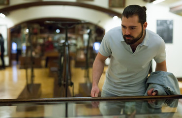 Adult man looking at exhibits in glazed stands in historical museum