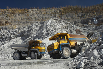 Two heavy quarry trucks inside a quarry for limestone mining, close-up. Heavy equipment. Mining industry.