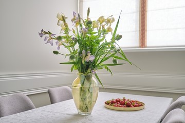 Home dining room interior, spring summer bouquet of flowers, strawberries