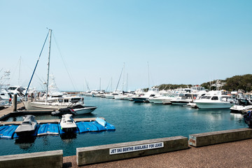 Fototapeta na wymiar Luxury yachts and fishing boats parked with a concrete walkway at pier of Nelson Bay