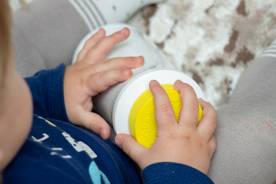 A Child Independently Tries To Open A Plastic Bottle Of Medicine, Close-up. Child-resistant, Childproof Or CR Packaging. Push&Turn Cap. Child Safety Concept