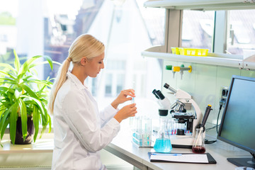 Female scientist working in modern lab. Doctor making microbiology research. Laboratory tools: microscope, test tubes, equipment. Biotechnology, chemistry, bacteriology, virology, dna and health care.