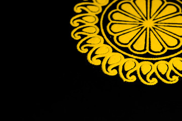side view of beautiful yellow rangoli on black background with copy space in left side. diwali concept