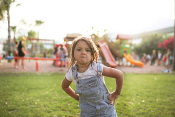 Funny stubborn summer girl child on walk on grass