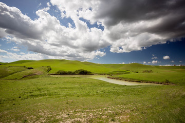 Colline Toscane con laghetto in primo piano immerso nelle verdi colline