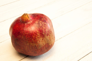 Red ripe pomegranate on a wooden table on a white background.