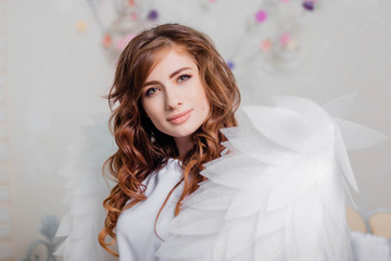 Portrait of a young girl in a white dress with angel wings.
