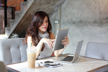 beautiful asian woman in casual dress shopping and online payment on tablet and computer while showing credit card in restaurant with happy smiling face