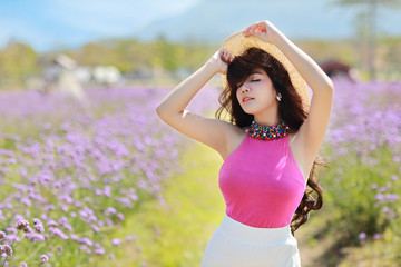 Asian beautiful woman, long hair in cute dress on Verbena filed in winter with blue sky. Beautiful cute girl portrait enjoying flowers in flowers farm background. Travel in nature outdoor concept.