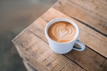 A beautiful cup of coffee with latte art in the wooden space background. Trendy toning. Minimal composition, hipster vibes. Top view, flat lay copy space for your text.