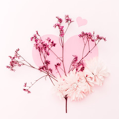 A large pink heart decorated with small pink flowers branch and some chrysanthemum on a pink tint background