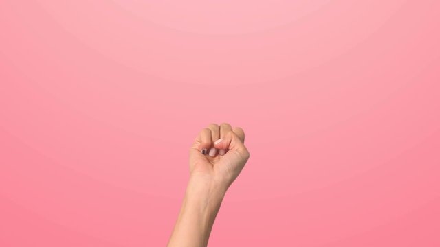 A woman's hand counts down from five to one on a pink background. Close up of a young girl's hand counting down the time