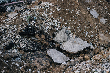 Destroyed asphalt. Repair the road. mountains of sand and stones