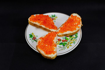Sandwiches with red caviar on a black background.