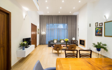 Modern interior of living room in private house. Big window. Wooden furniture. Doors. View from the staircase.