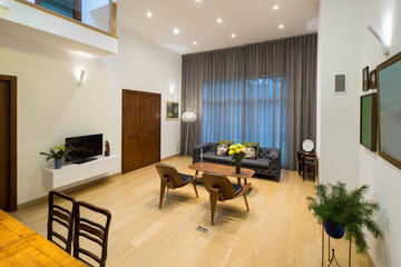 Modern interior of living room in private house. View of wall with big window. Furniture and TV.