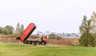 Fototapeta premium A large 70-ton dump truck brought sand to a new construction site to add land