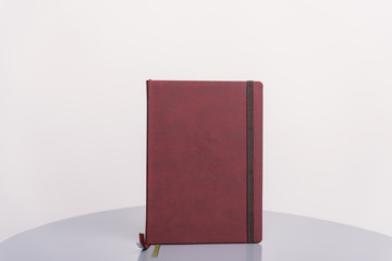 Brown book, agenda or planner standing on a grey surface and white background. Book template.
