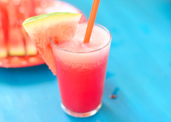 Watermelon juice with a straw over blue background