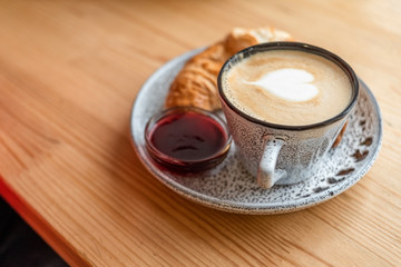 Obraz na płótnie Canvas cup of cappuccino with croissant on a wooden windowsill