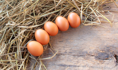 Close-up 5 eggs put on straw with wooden background
