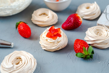Strawberry pavlova cake nests, meringue decoration on a culinary table