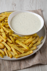 Homemade Crispy Ranch Fries on a gray plate on a white wooden background, low angle view. Close-up.