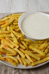 Homemade Crispy Ranch Fries on a gray plate on a white wooden surface, low angle view. Close-up.