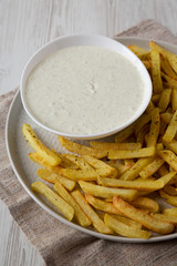 Homemade Crispy Ranch Fries on a gray plate on a white wooden table, low angle view. Close-up.