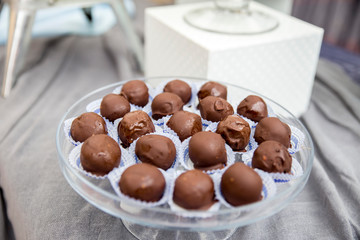 A closeup of rum balls on a plate on the table under the lights with a blurred background