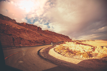Winding mountain road with dramatig sky. Makhtesh Ramon Crater in Negev desert at sunset, Israel