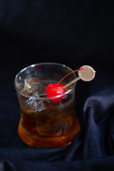 Manhattan with a Cherry Garnish.Black cloth backdrop