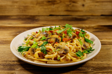 Pasta with mushrooms and tomato sauce on wooden table