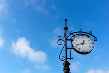 Fototapeta na wymiar city clock on a pole against the blue sky
