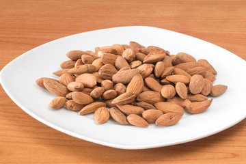 Almonds on white plate on table. Delicious and healthy protein-rich diet food.