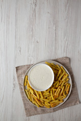 Homemade Crispy Ranch Fries on a gray plate on a white wooden table, top view. Overhead, from above. Copy space.